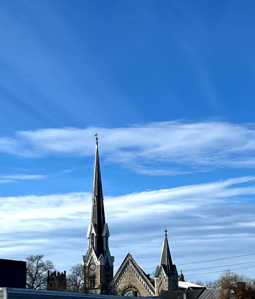 Church steeple against a blue sky with banks of white clouds 