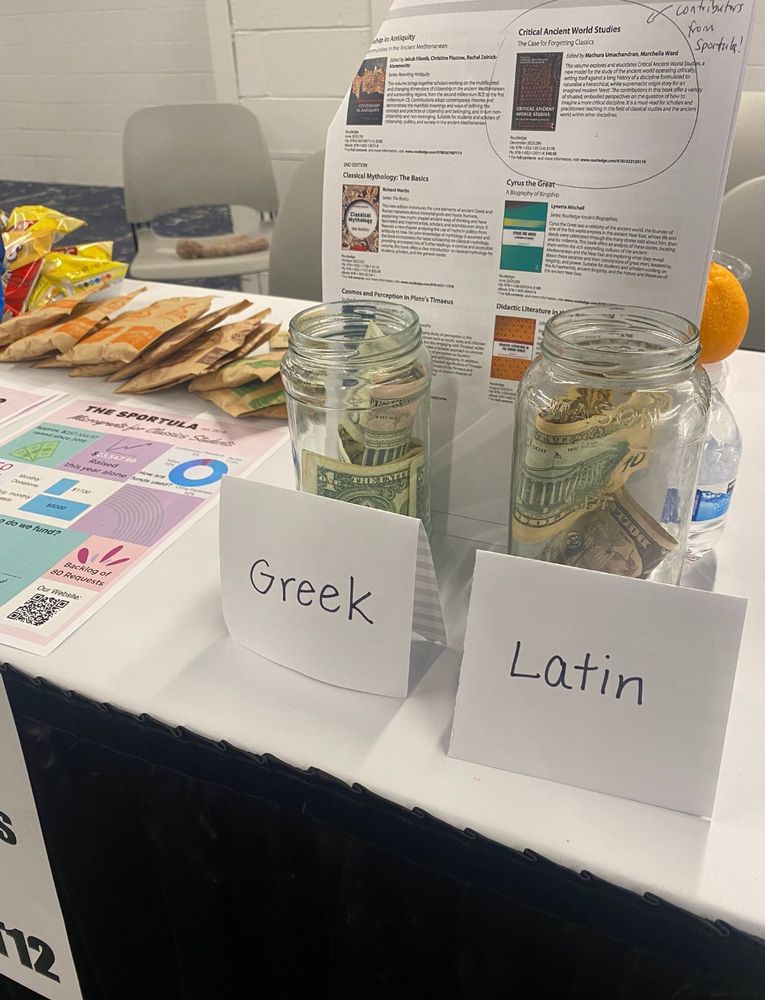 Two glass jars filled with cash labeled GREEK and LATIN