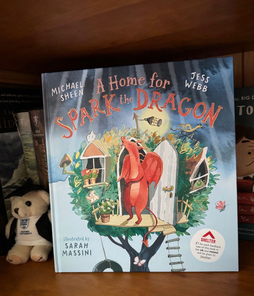A child’s book “A Home for Spark the Dragon “ standing on a brown bookshelf.