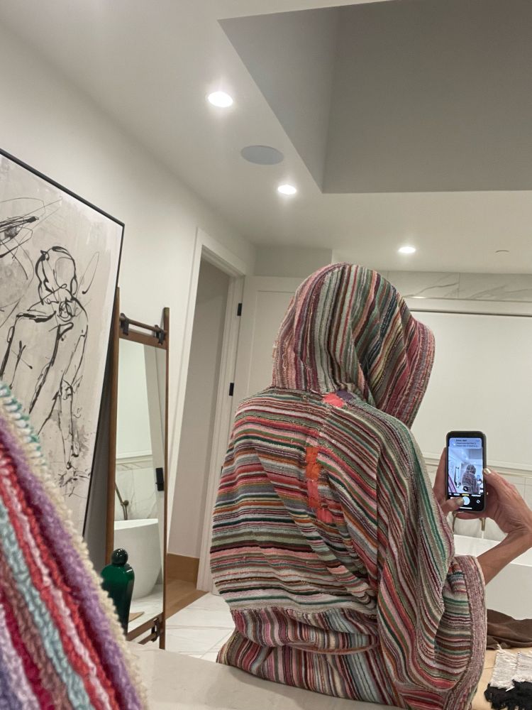A photo of me, hooded in a rainbow robe, from the back, in double mirrors