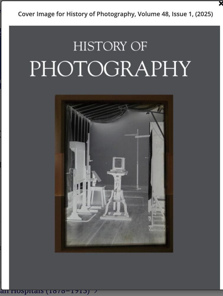 Cover image for History of Photography volume 48 issue 1 (2025). The background is grey. At the top it says History of Photography in white. In the middle of the page there is a glass plate negative of a photo studio. You can see a camera on a tripod, several other devices on the sides, and the stage, with more devices.