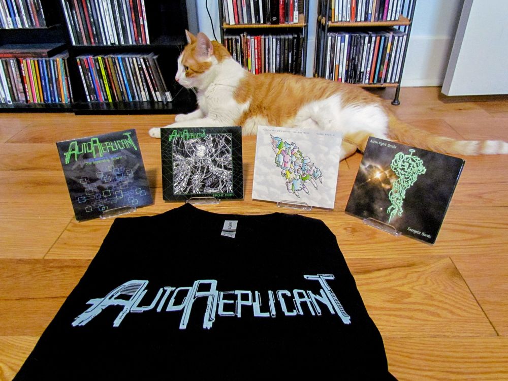 A cat sits behind merch that is available for Bandcamp Friday.