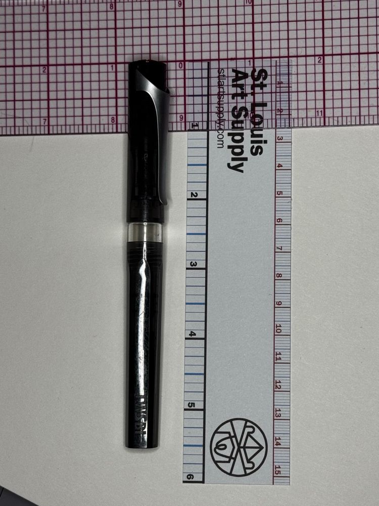 A black twibi fountain pen against two rulers in inches