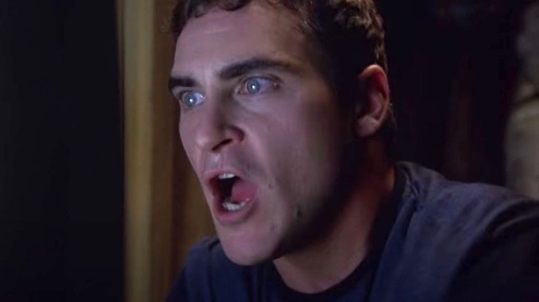 Screencap from the movie Signs of the scene where Joaquin Phoenix yells at kids on TV to run after they see an alien in the alleyway