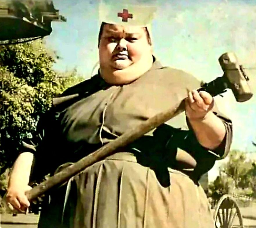 Eine dicke Krankenschwester steht da bedrohlich mit einem großen Hammer 