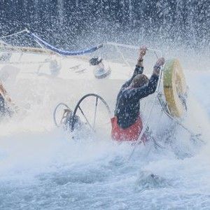 A scene from Robert Redford's movie "All Is Lost".  Caught in a heavy storm, a man desperately clings to the railing of his partially-capsized sailboat.