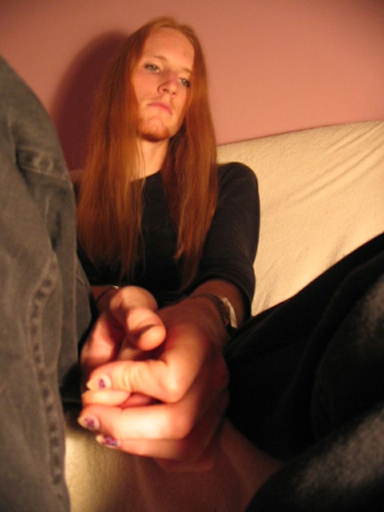 Low shot of me on the couch. I'm looking down. My hands are together slightly awkwardly. My nails are pointy and old nail polish has mostly chipped away.