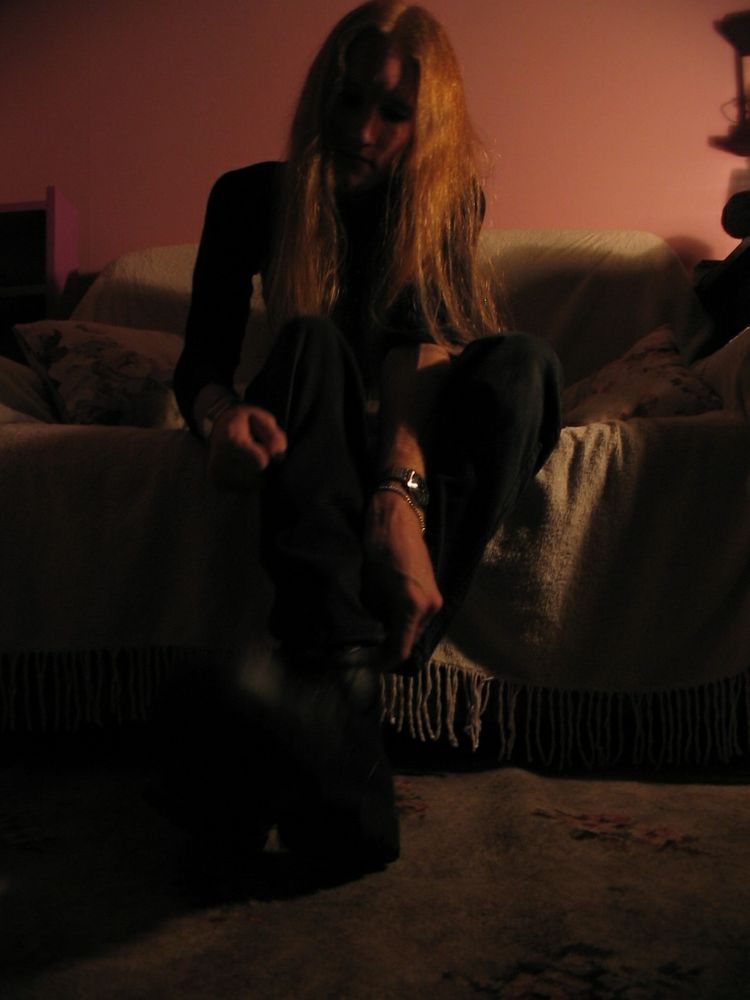 Still on the couch but leaning forward. My face is in shadow. I'm reaching a hand down for some reason.