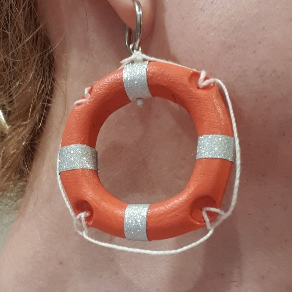 Close-up of one of the lifebouy earrings hanging from my ear. It's a basic 'doughnut' shape made with polymer clay, with four, evenly-spaced indents for the 'rope' to connect. It's painted orange with some silver, glittery washi tape. Some white string is attached to replicate the 'rope'.

These worked out much better than expected? I had never worked with polymer clay before. And they are fairly heavy, but not too heavy on my ears - even when dancing up and down for hours.

Sadly, the event was so dark so few people would casually see them.