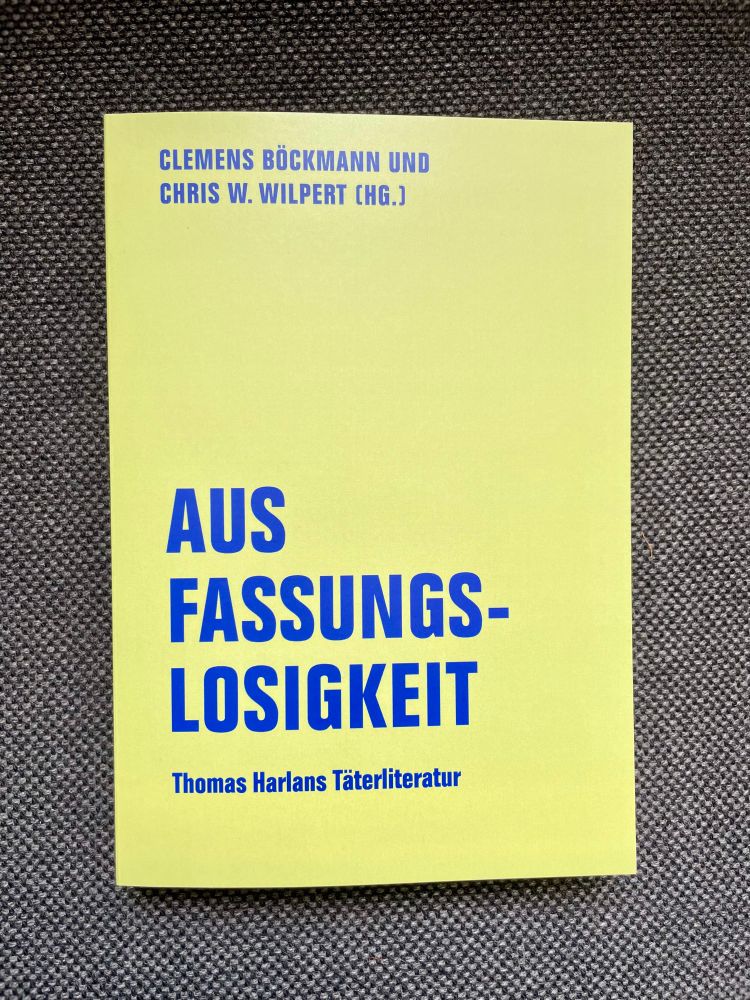 Das Buch, blaue Schrift auf hellgrünem Grund, auch dunklem Stoff liegend 