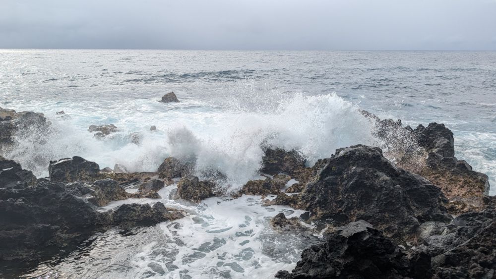Waves crashing over volcanic rocks.