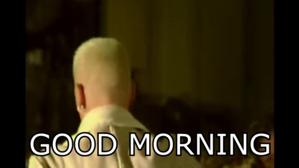 a man is sitting on a couch with the words `` good morning '' written on the bottom .