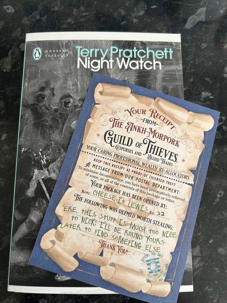 A copy of the new Penguin edition of Night Watch by Terry Pratchett. Lying on top of it is a certificate from the Ankh Morpork Thieves Guild