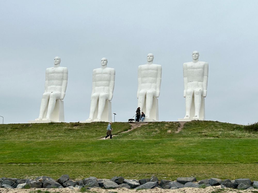 4 große Menschenstatuen auf einem grün bewachsenen Hügel