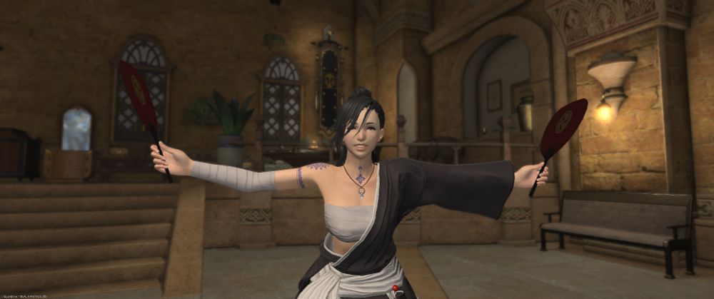 A cheerful Hyur Midlander woman poses indoors in a warmly lit room, holding two festival fans out wide with a bright smile. She wears a black and white kimono-style outfit with red accents, and a blue flower-shaped tattoo is visible on her chest. The background shows the interior of the Squadron Room of the Immortal Flames with stone walls, arched windows, and decorative furniture.