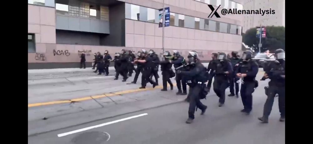 LAPD Police line on the street near wall with graffiti reading acab near the ICE facility in downtown Los Angeles 