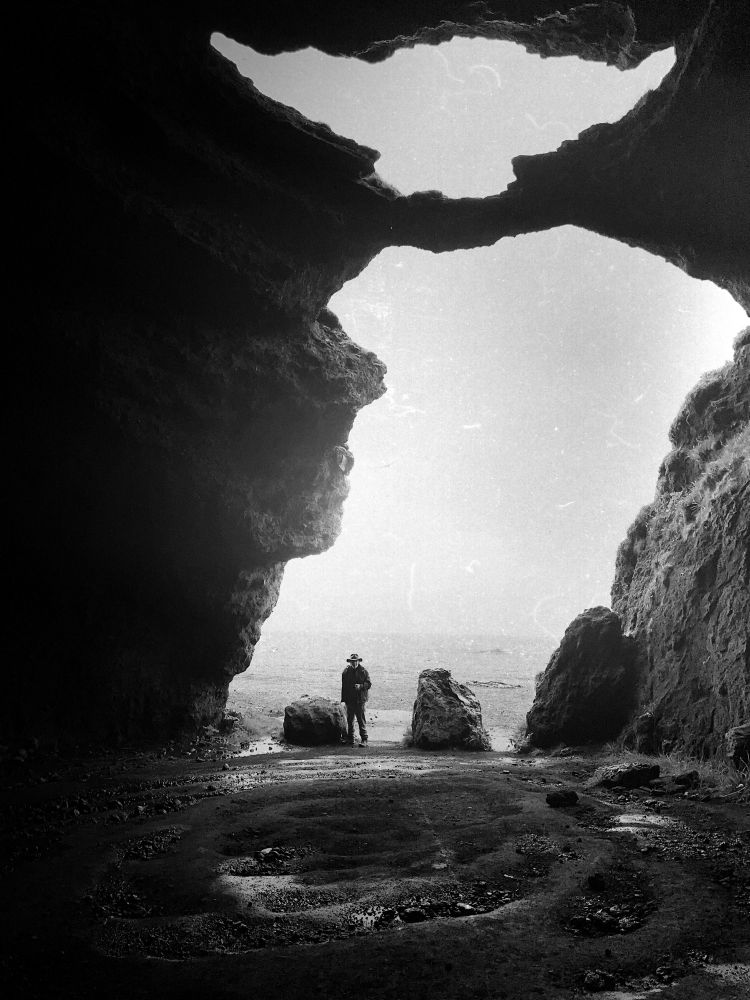 Black and white image taken from the inside of the Yoda Cave near Vik, Iceland showing a striking opening in the shape of Yoda’s profile.