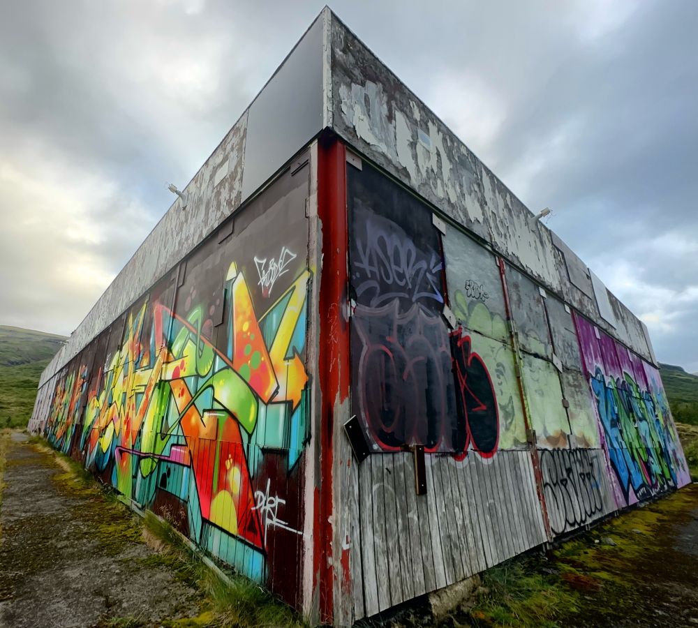 Perspective view of an abandoned building in Iceland with colorful graffiti art.