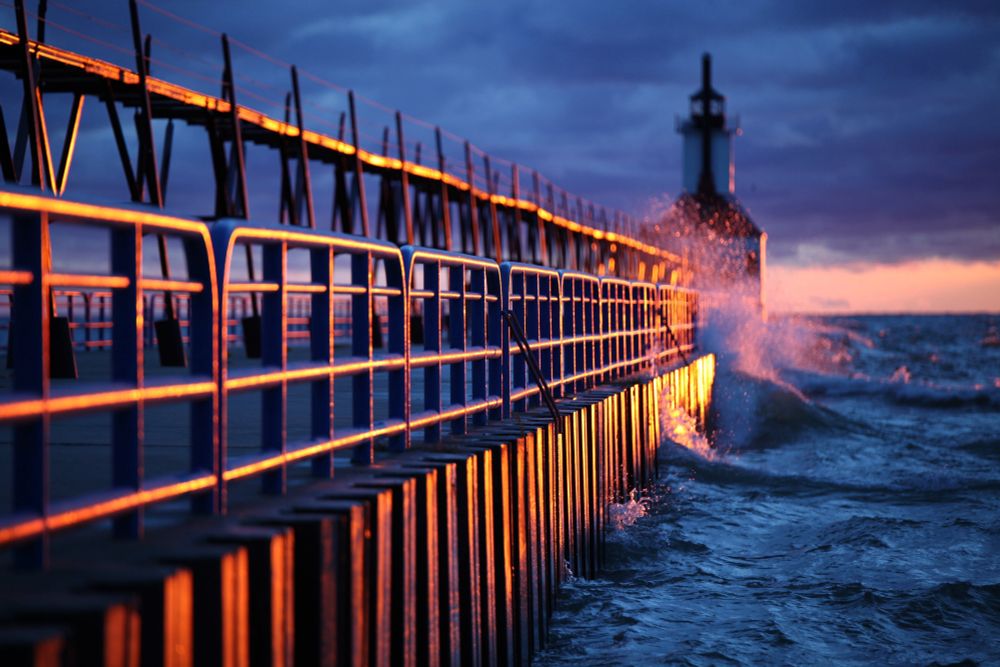 Vibrant color image of a lighthouse at sunset with strong visual elements of guard rails.