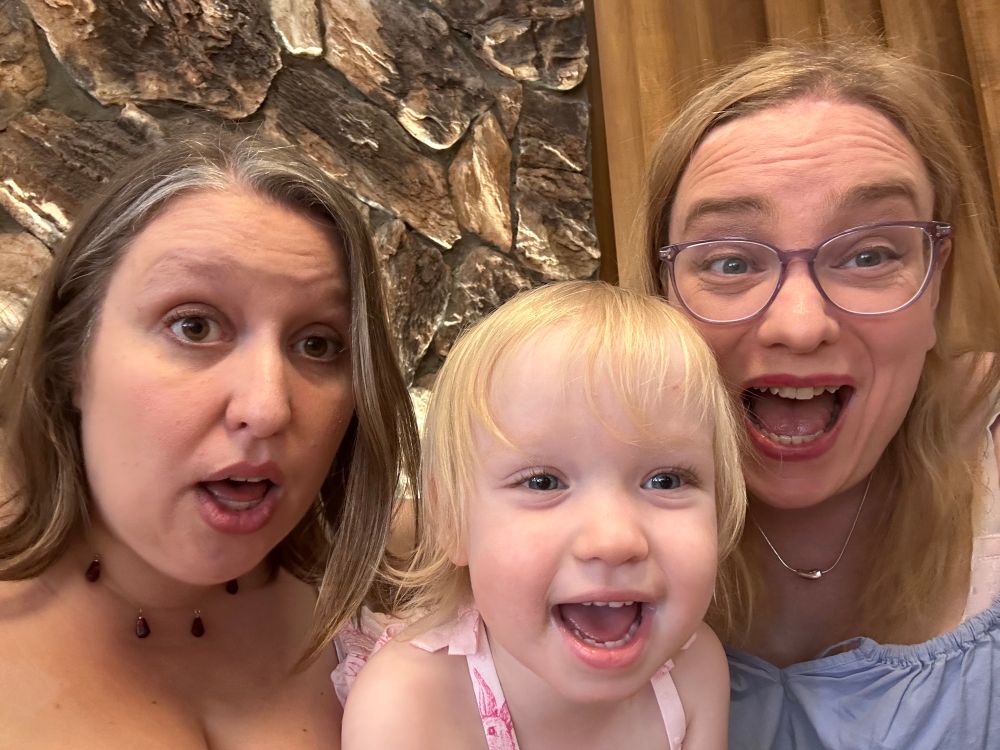 Emily and her wife and kid, all dressed in Easter finery, mug for the camera.