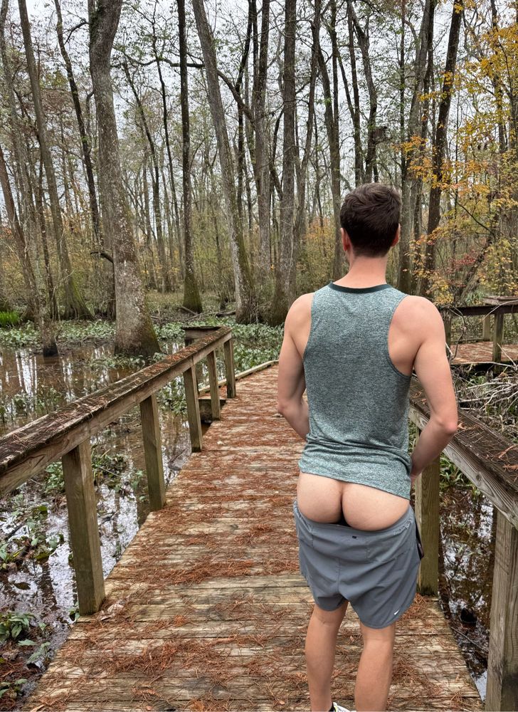 Man on boardwalk in swamp with shorts down