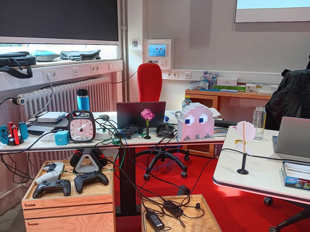 A photo of our desks, where we'd sit occasionally to give short inputs on a range of topics. There's a lot of gaming technology on top and in front of the desks, as well as game-related accessories and decoration.
