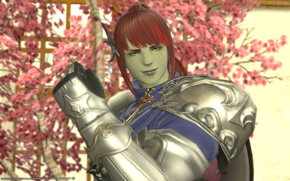 A screenshot of Imry, a Roegadyn woman with green skin and freckles, and red hair. She's smiling in a friendly way and gesturing encouragingly.