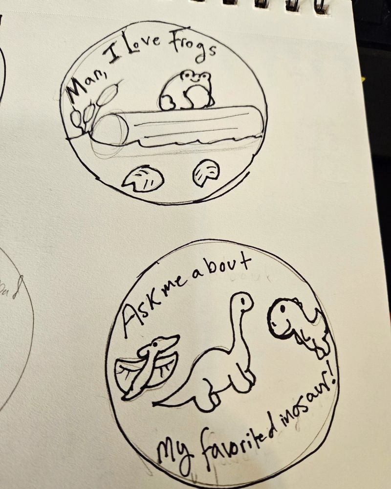 Sketch page of sticker designs. One says "man I love frogs" with a frog on a log in a pond. The other says "ask me about my favorite dinosaur" and has a t rex, brontosaurus, and a pterodactyl.