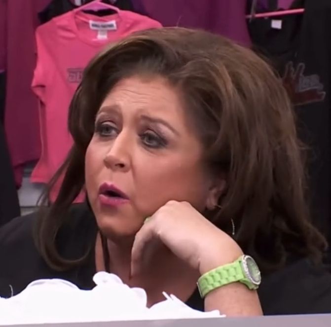 Frame from Dance Mom of Abby Lee Miller sitting at the reception desk in her Dance Studio talking to the Moms which she said "Melissa, you don't even sew. You have zero talent!"