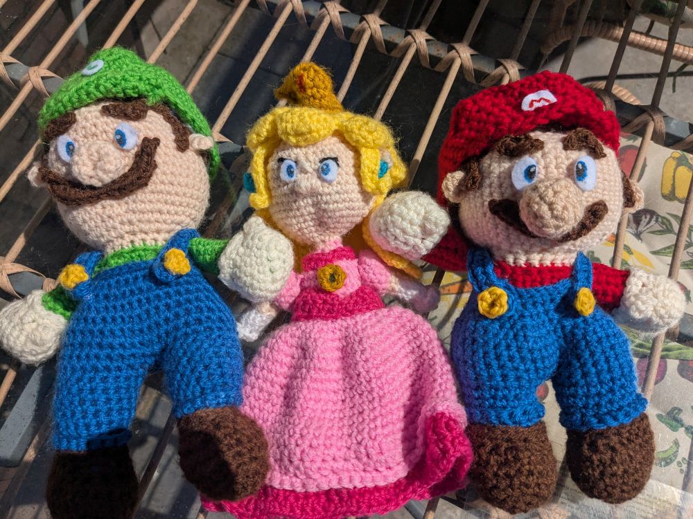 3 crochet dolls of the characters Luigi, Princess Peach and Mario from the super Mario Brothers games