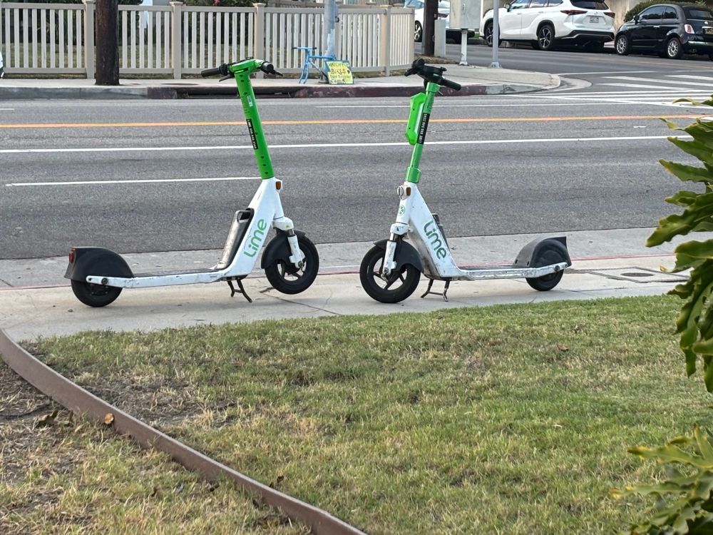 Two bird (or lime or whatever) scooters kissing 
