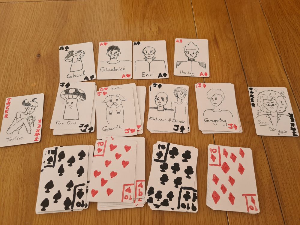 The hand drawn cards I created! (This is specifically Dave Hearn's deck.) Displayed in 3 rows (with two jokers on the side), the cards are as follows:
Row 1 (left to right):
Ace Of Spades: Ghoul
Ace Of Hearts: Gluebrick
Ace Of Clubs: Eric
Ace Of Diamonds: Henley
Row 2 (left to right):
Jack Of Spades: Fun Gus
Jack Of Hearts: Garth
Jack Of Clubs: Malvor and Dorex
Jack Of Diamonds: Gregothy
Row 3 (no characters) (left to right):
10 Of Spades, 10 Of Hearts, 10 Of Clubs, 10 Of Diamonds.
The Red Joker is Tootsie
The Black Joker is Scarafax.