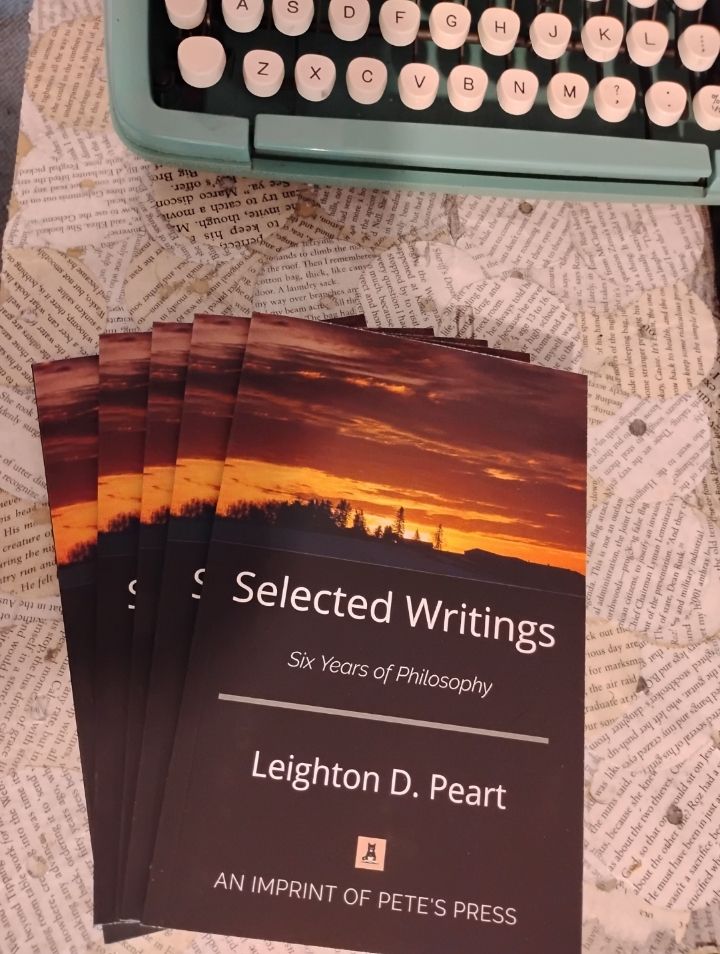 A stack of copies of Selected Writings by Leighton Peart. The cover is black with a sunset over a Toronto skyline at the top.