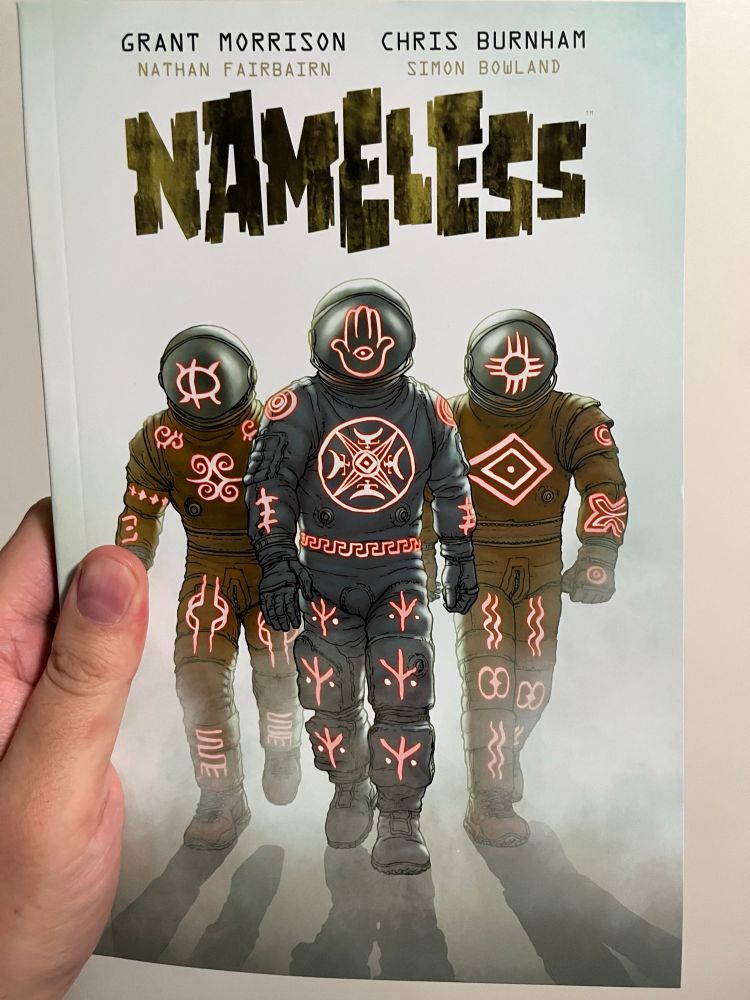 An image of the cover of Nameless by Grant Morrison, Chris Burnham, Nathan Fairbairn, and Simon Bowland. The cover image is three people in spacesuits that are covered in glowing runes. 