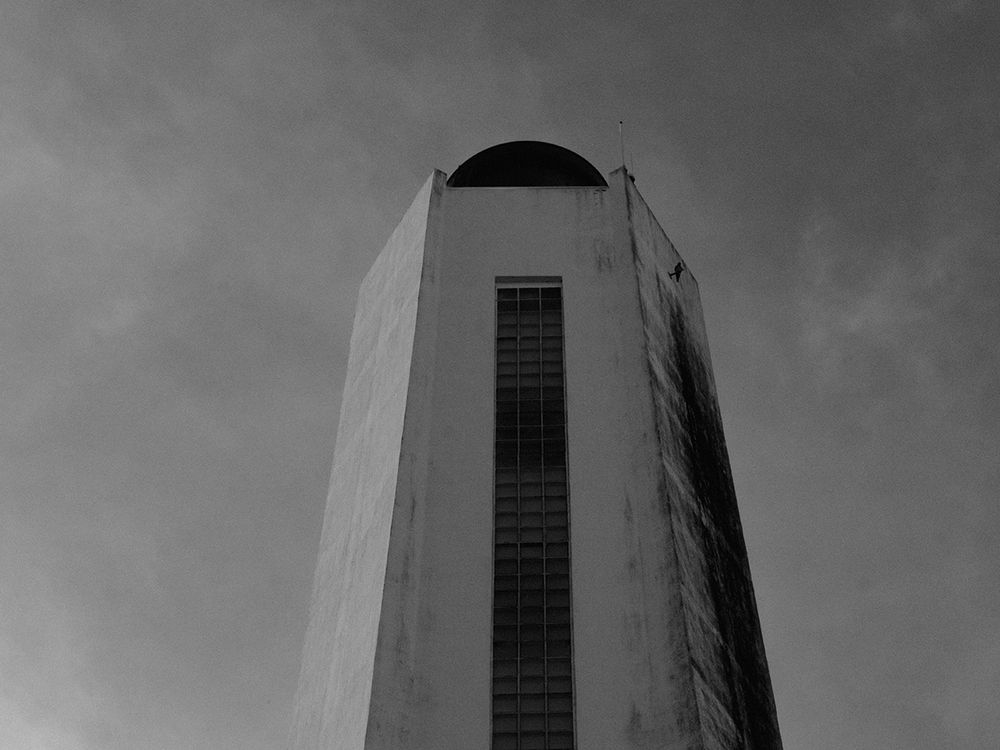Photo en noir et blanc de la tête du phare prise en contre-plongée depuis son pied.