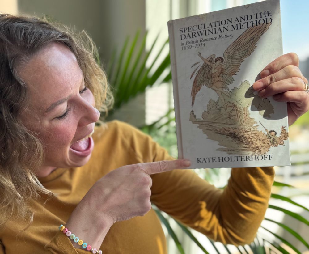 Rachel, holding Kate’s awesome new book Speculation and the Darwinian Method in British Romance Fiction 1859-1914