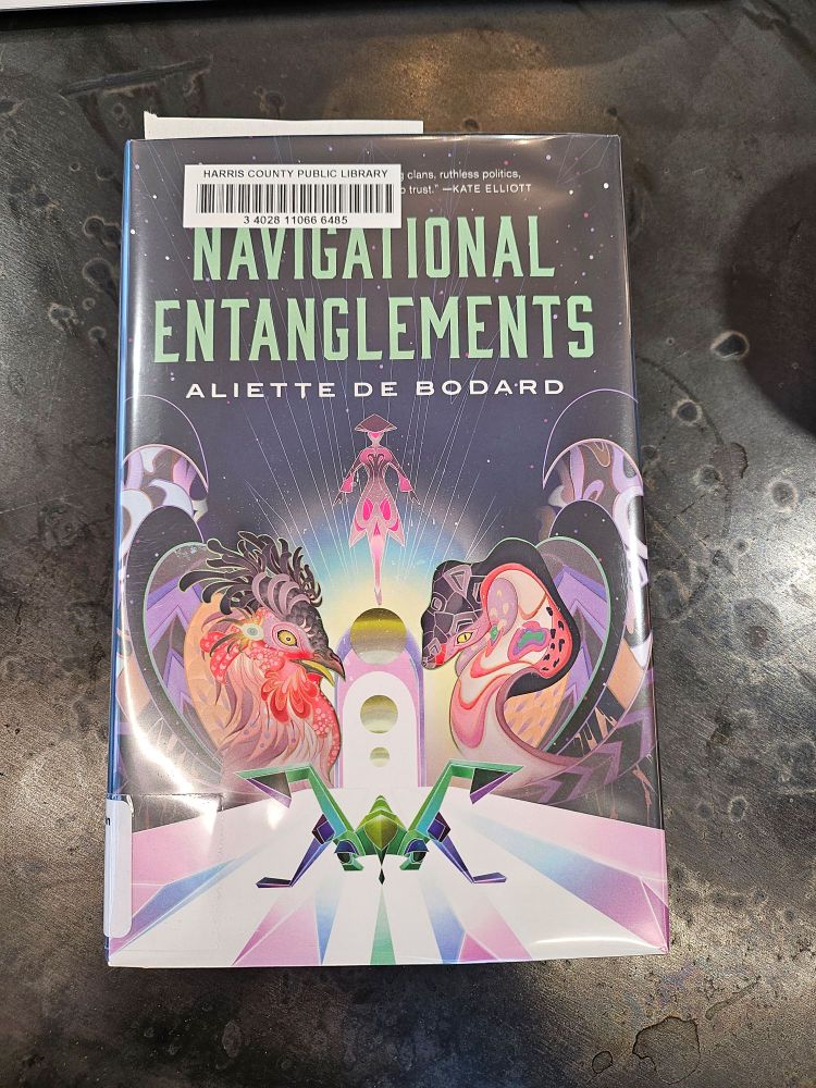 Library copy of Navigational Entanglements by Aliette de Bodard, sitting on a black coffee shop table background.