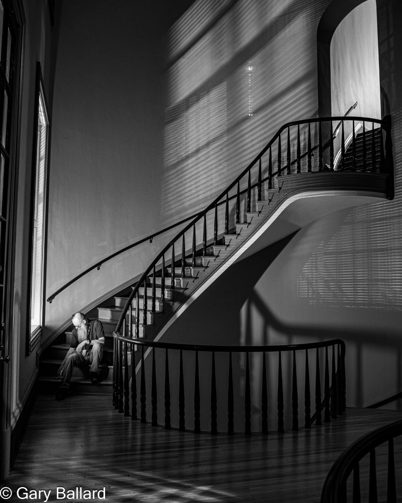 I sit on the stairs of the Old Capitol Museum in black and white.