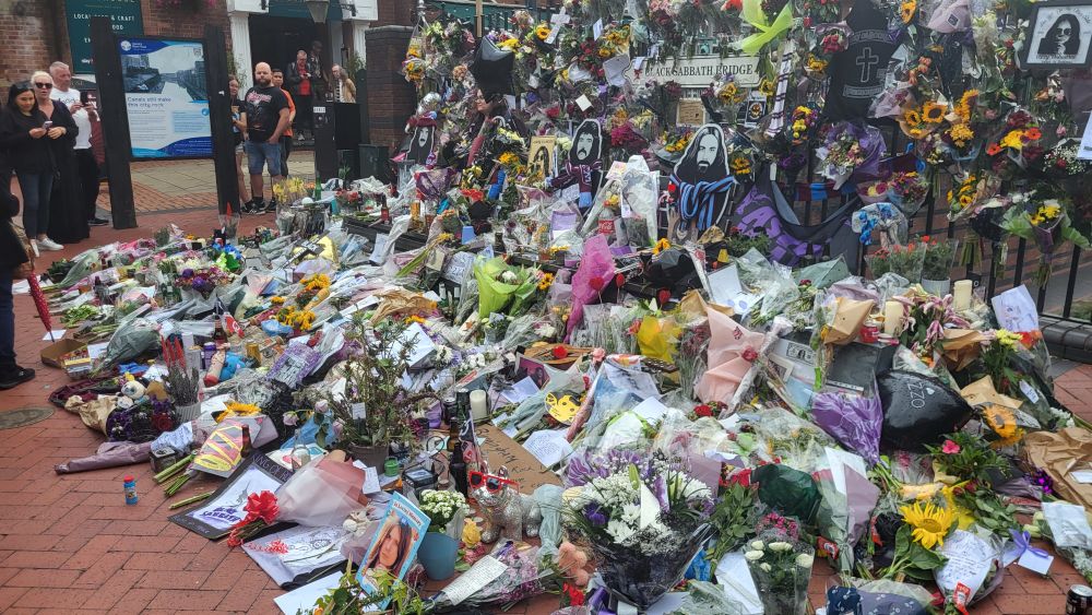 The Black Sabbath bench surrounded by flowers and candles as well as other tributes to Ozzy Osbourne 