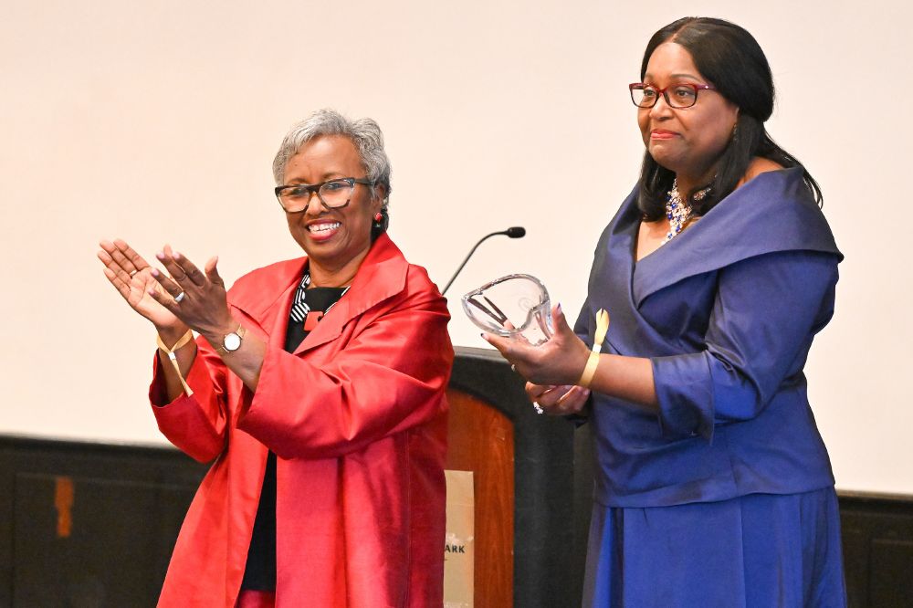 The Rev. CeCe Armstrong holds her award as Dr. Phyllis W. Sanders stands beside her applauding. 