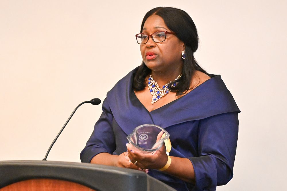 The Rev. CeCe Armstrong holds her award as she speaks at a podium.