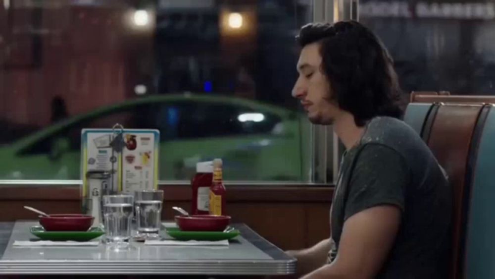 a man is sitting at a diner table with a menu in the background