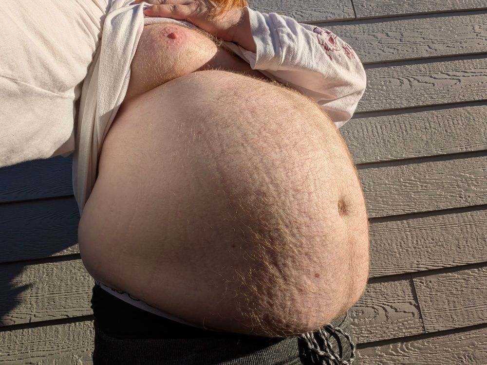 Me showing off a selfie of my tummy with my shirt pulled up past my chest in the sunlight 