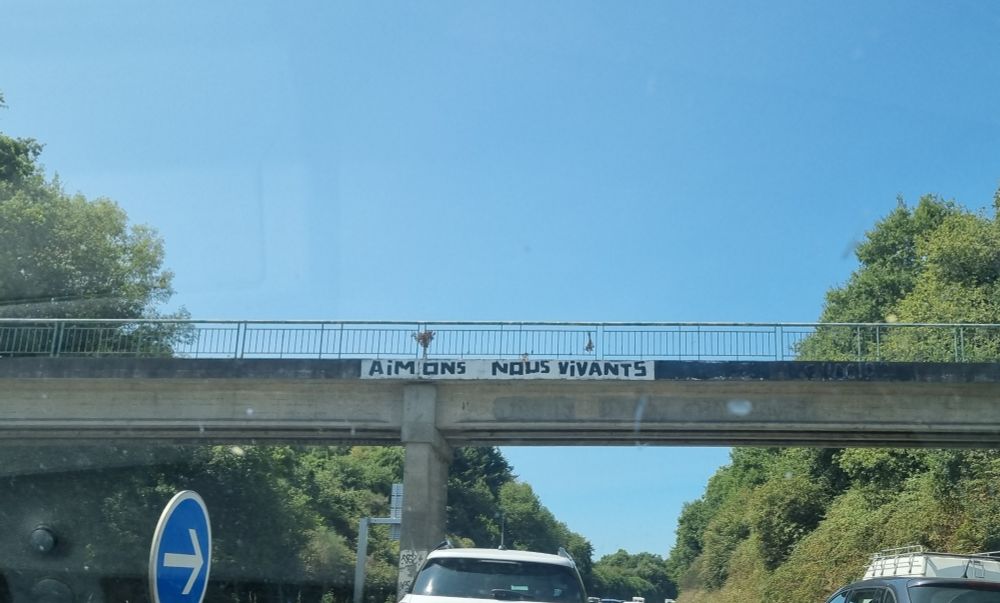 "Aimons nous vivants" message sur passerelle de route 