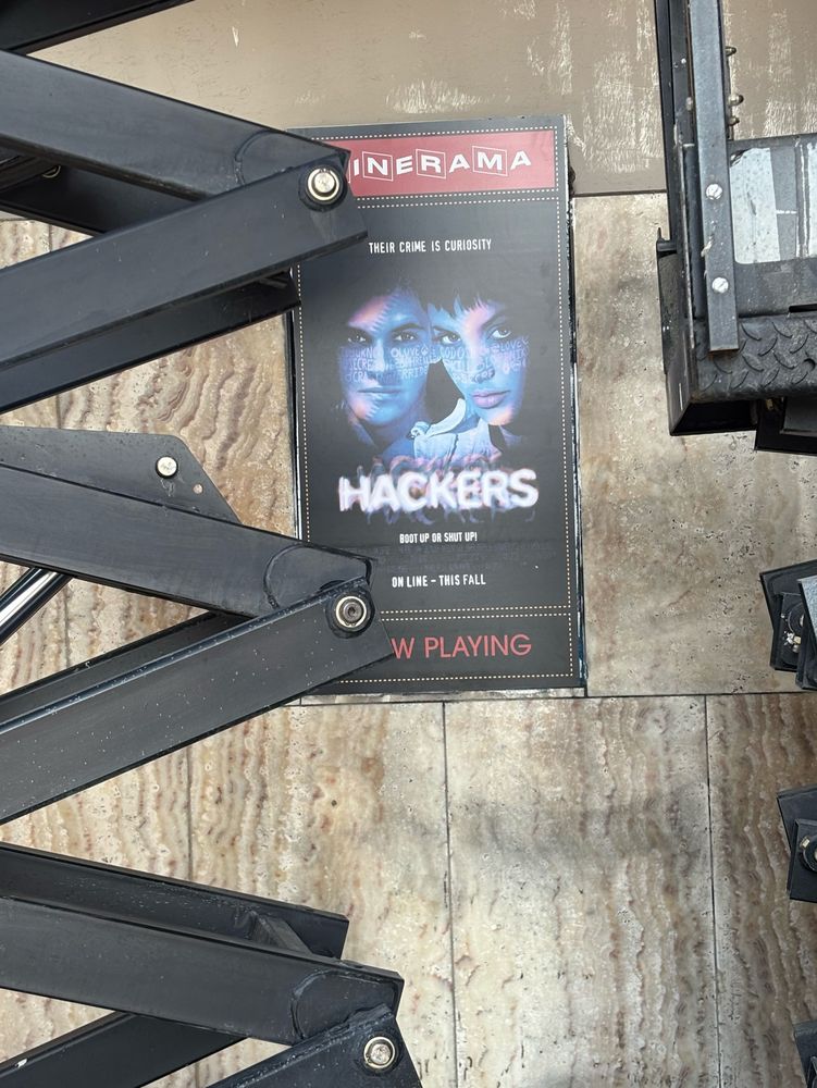 Construction lifts frame a movie poster for 90s classic, “Hackers”