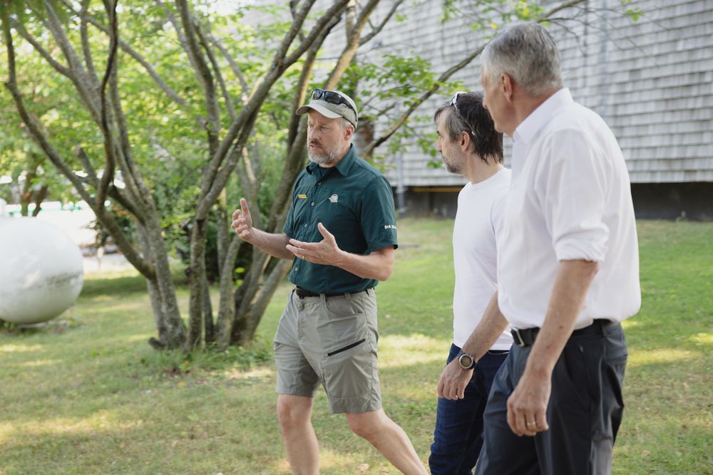 Parks Canada staff member (left), Minister Guilbeault (centre) and MP Fanjoy (right) talking while walking.