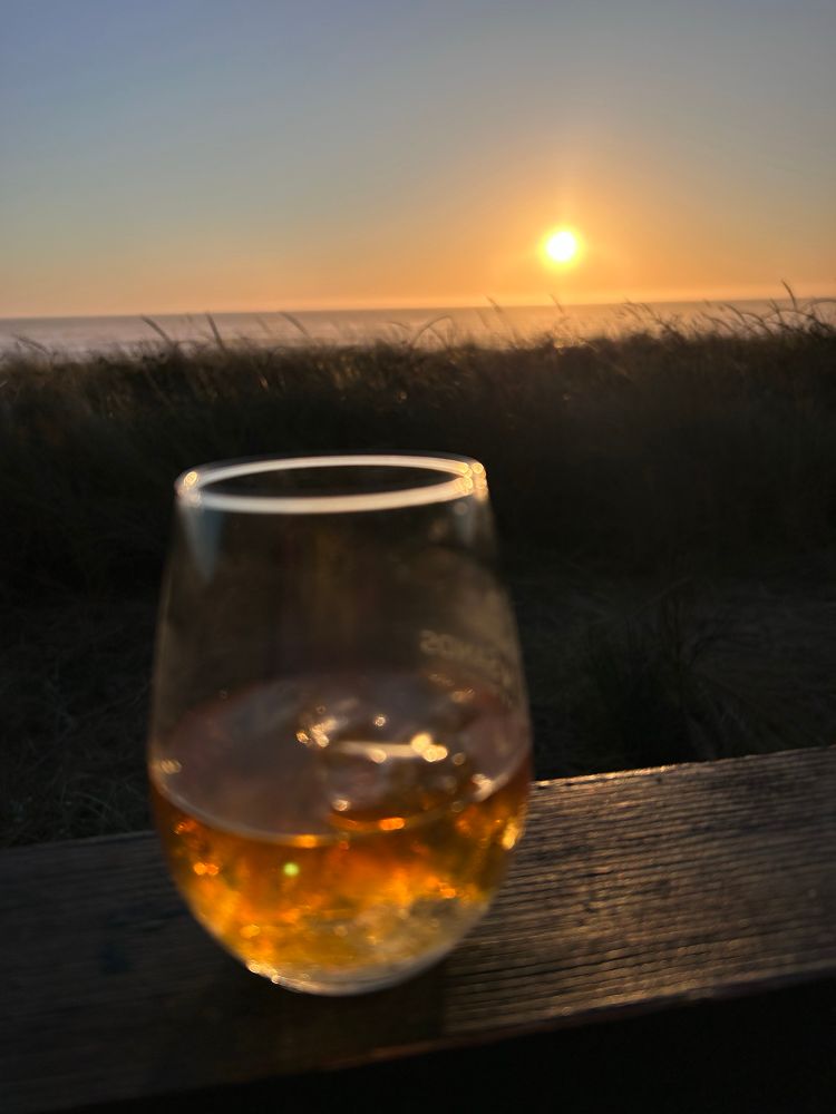 An out of focus bourbon in front of a beautiful near sunset 