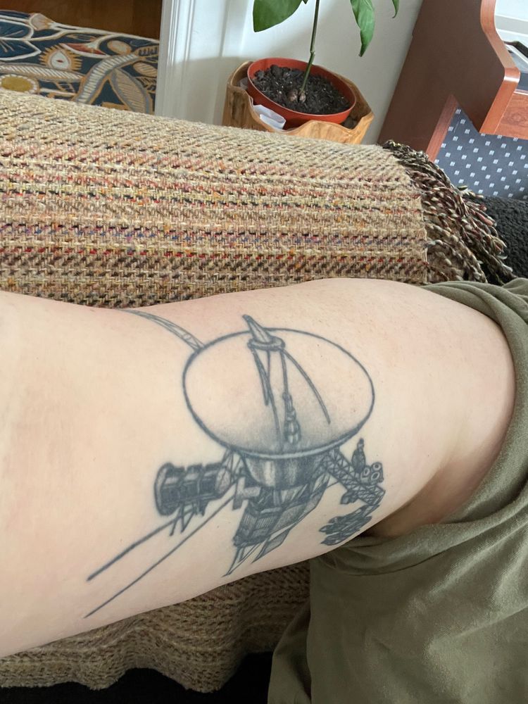 Photo of a black ink tattoo on my inner right bicep of the Voyager II space probe.