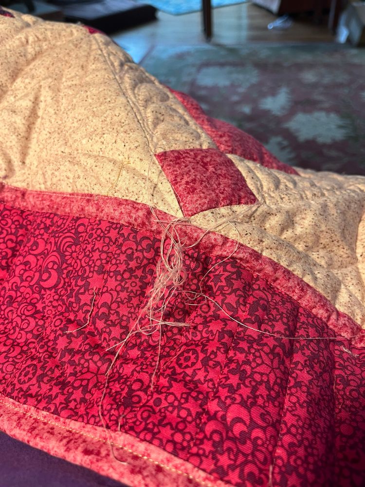Messy Thread nest lying on a pink and white quilt. At least 16 threads in that mess. 