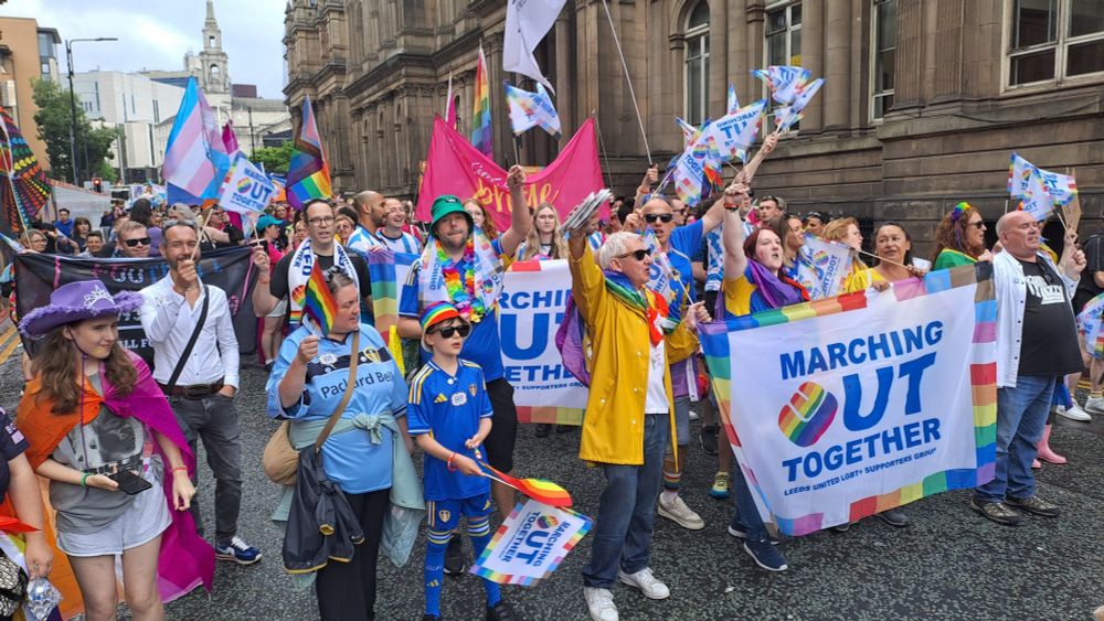 Marching Out Together group with flags and banners at Leeds Pride